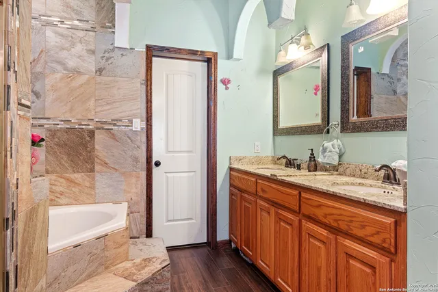 a bathroom with a granite countertop sink mirror and a bathtub