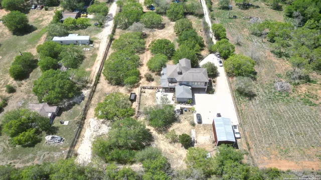 an aerial view of residential house with outdoor space and trees all around