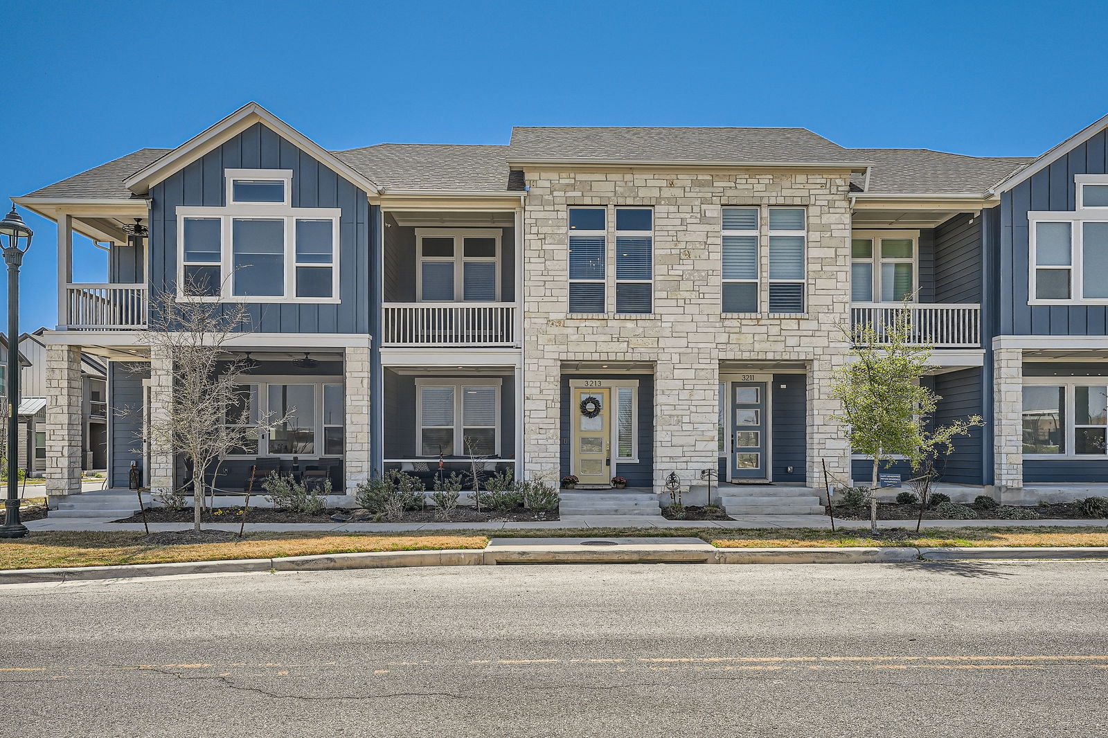 Townhome / multi-family property featuring a shingled roof, stone siding, and board and batten siding