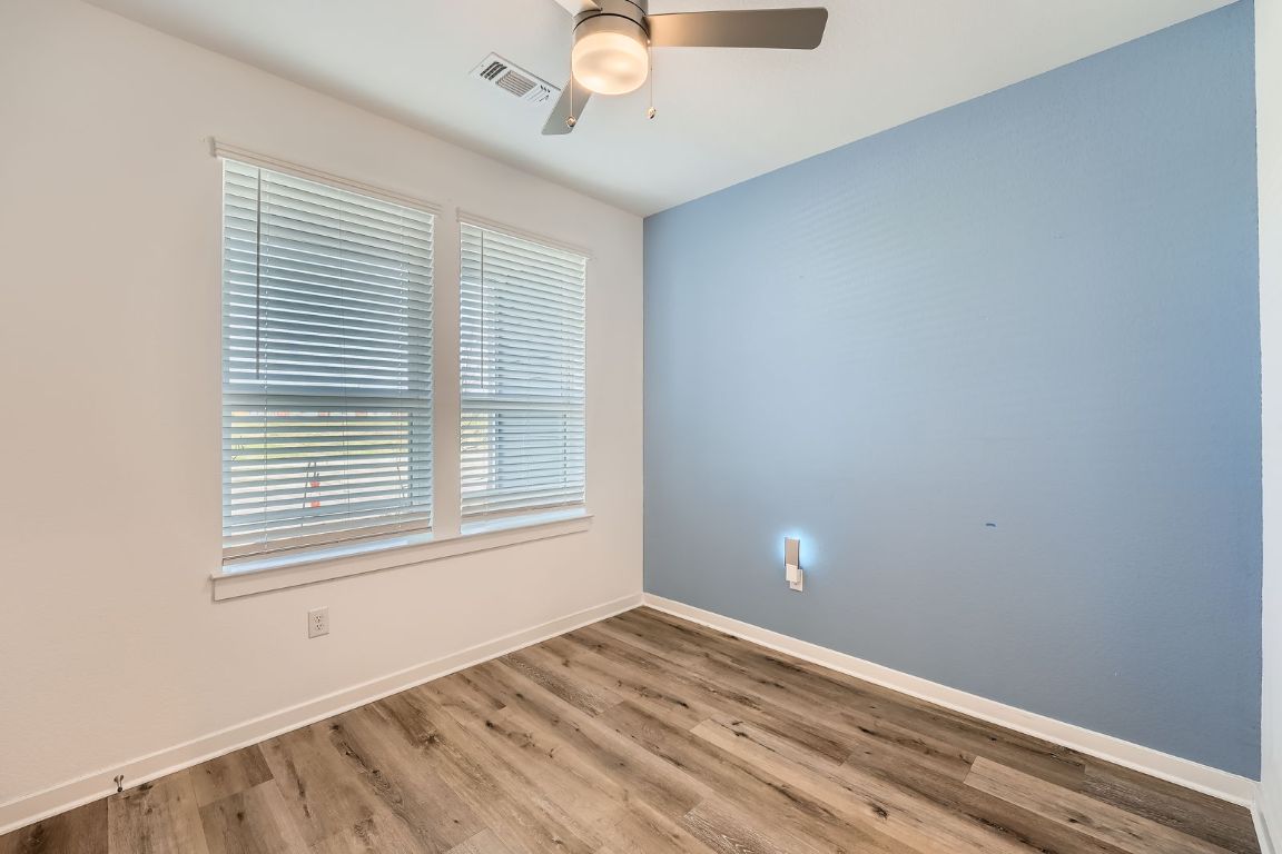 3213 Zach Scott Street Austin, TX 78723 - Photo 9 of 28 Spare room with wood finished floors, baseboards, ceiling fan, and visible vents