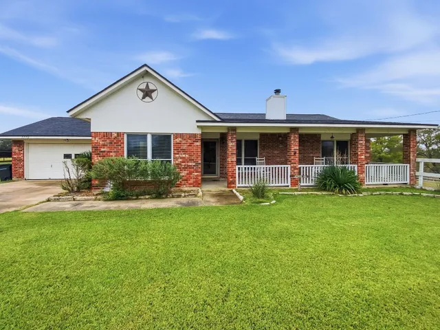 a front view of a house with a yard and green space