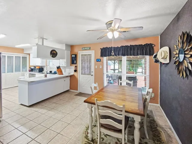 a kitchen with a table chairs and a ceiling fan