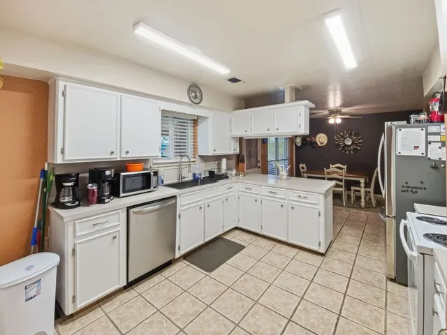 a kitchen with white cabinets a counter space and appliances