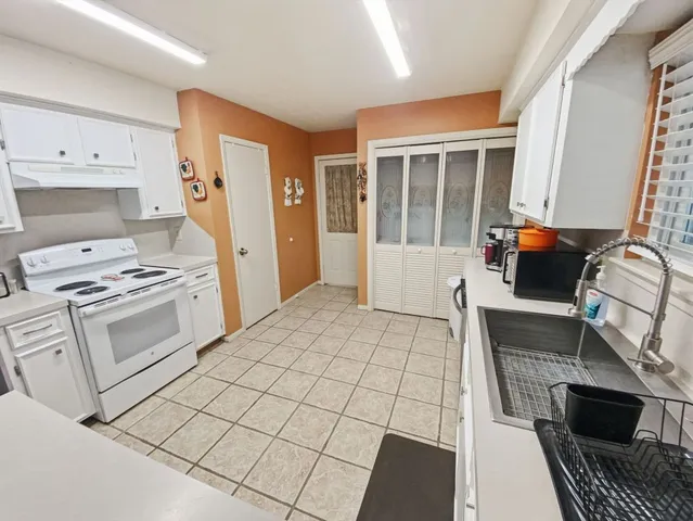 a kitchen with granite countertop a stove a sink and a refrigerator