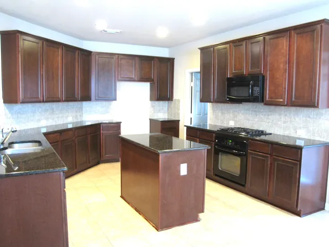 a kitchen with stainless steel appliances granite countertop wooden cabinets a stove top oven a sink and dishwasher