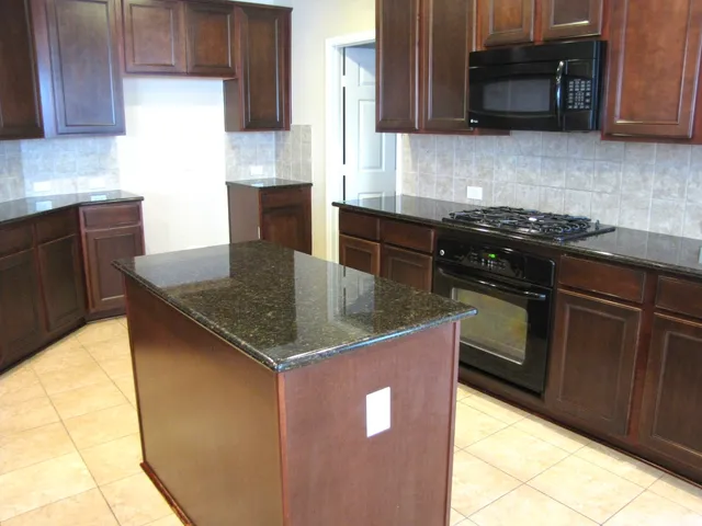 a kitchen with granite countertop a stove a sink a microwave and cabinets