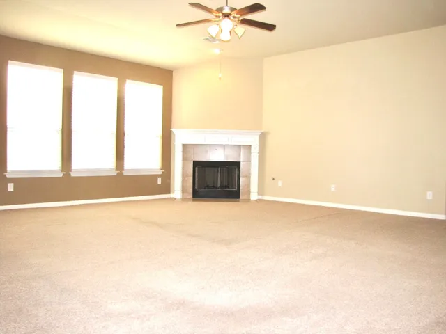 an empty room with windows and fireplace
