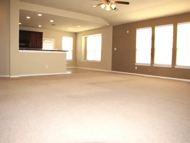 an empty room with windows and ceiling fan