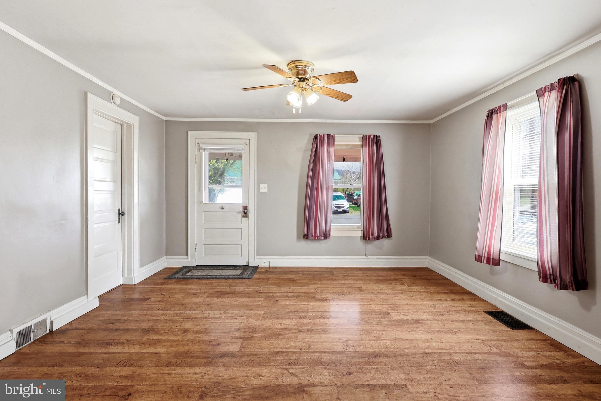 715 Charles Street Romney, WV 26757 - Photo 8 of 44 a view of an empty room with window a ceiling fan and wooden floor