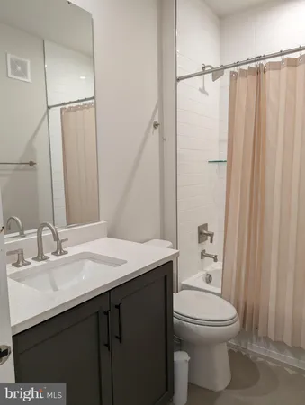 a bathroom with a sink a toilet a mirror and shower curtain