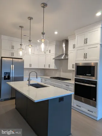 a kitchen with stainless steel appliances granite countertop a sink a stove a refrigerator and white cabinets