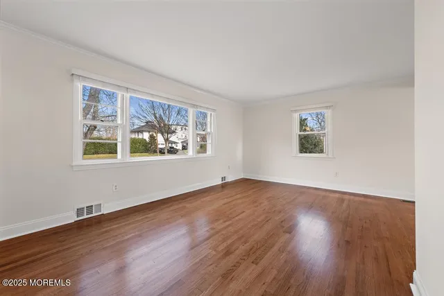 an empty room with wooden floor a ceiling fan and windows
