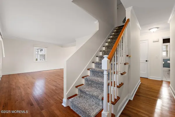 a view of a hallway with wooden floor and staircase