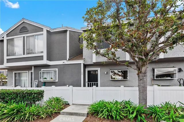 front view of a house with potted plants and a large tree