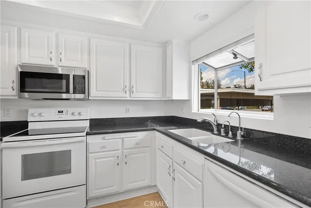 a kitchen with granite countertop white cabinets and white appliances