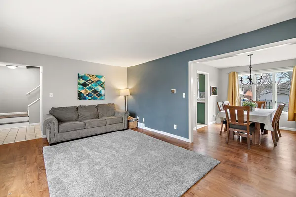 a living room with furniture and a dining table with wooden floor
