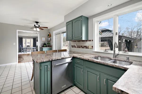a kitchen with granite countertop a sink and a white wooden cabinets