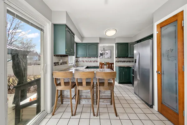 a dining area with stainless steel appliances a table chairs and chandelier