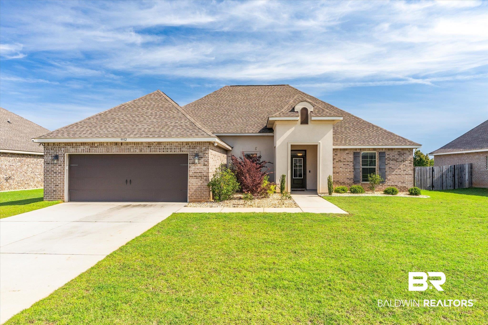 French country home featuring roof with shingles, brick siding, and concrete driveway