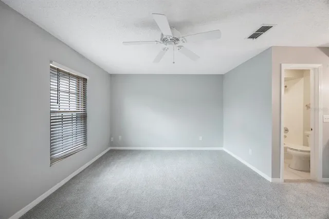 an empty room with a window and a ceiling fan