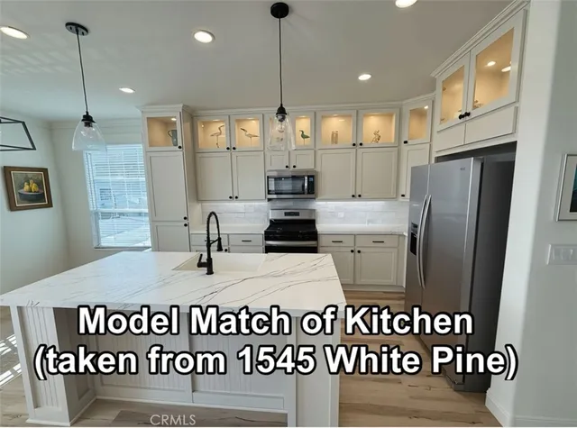 a kitchen with kitchen island a counter space a sink appliances and cabinets