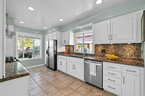 a kitchen with granite countertop a refrigerator and white cabinets