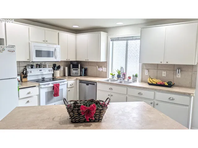 a kitchen with kitchen island granite countertop a sink dishwasher stove and white cabinets