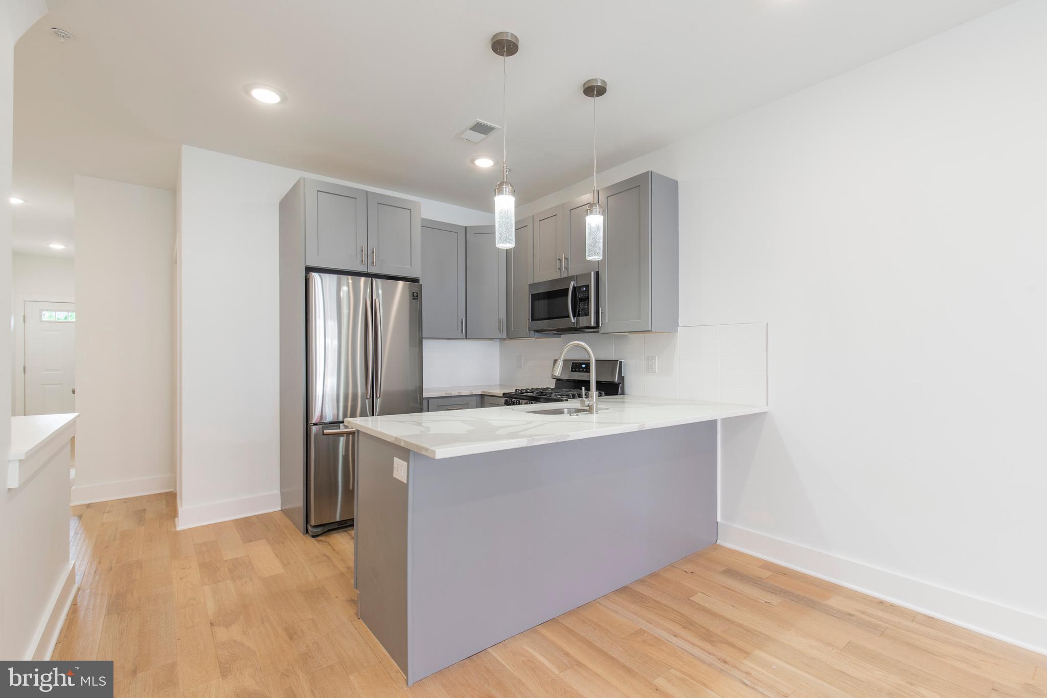 2412 Master Street, Unit A Philadelphia, PA 19121 - Photo 6 of 25 a kitchen with stainless steel appliances a sink stove and refrigerator
