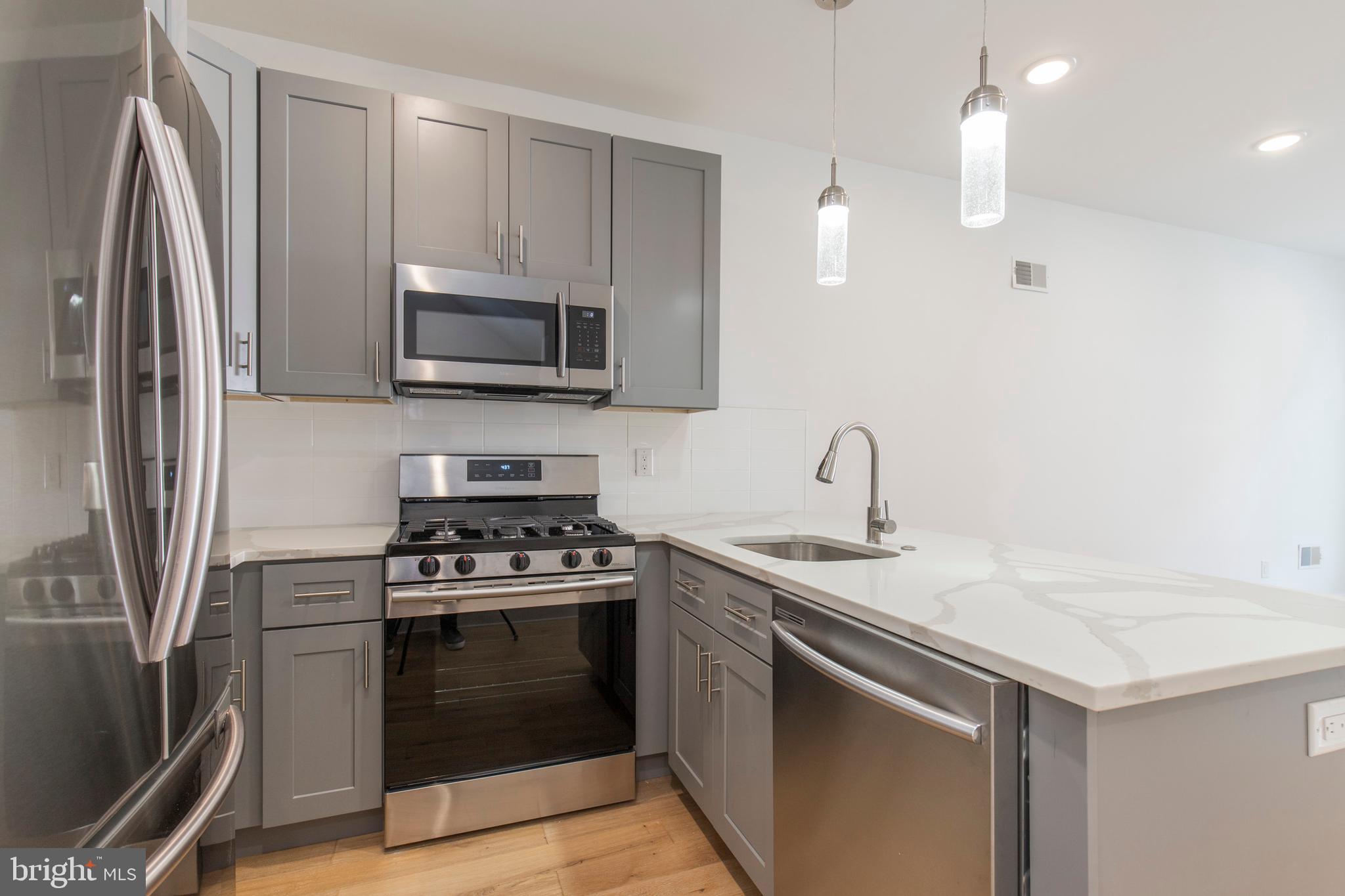 2412 Master Street, Unit A Philadelphia, PA 19121 - Photo 7 of 25 a kitchen with stainless steel appliances a stove microwave and a refrigerator