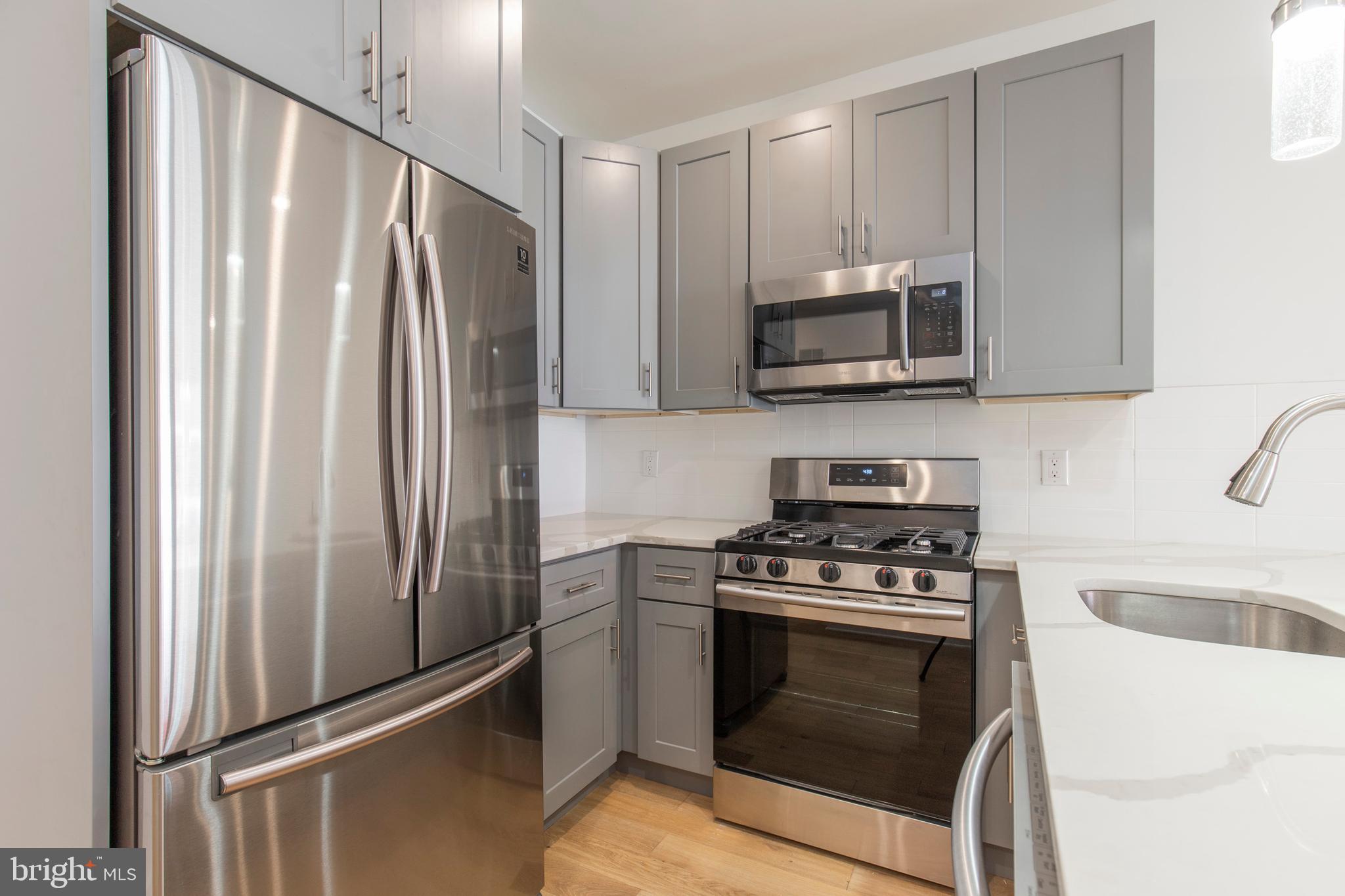 2412 Master Street, Unit A Philadelphia, PA 19121 - Photo 8 of 25 a kitchen with stainless steel appliances white cabinets and a stove top oven
