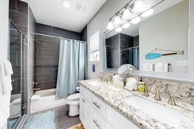 a bathroom with a granite countertop sink a toilet a mirror and shower