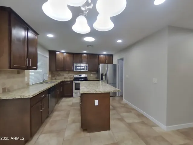 a kitchen with kitchen island stainless steel appliances a sink cabinets and a counter top