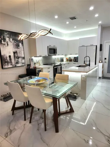 a living room with stainless steel appliances furniture a rug and a kitchen view