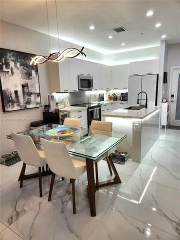 a living room with stainless steel appliances furniture a rug and a kitchen view
