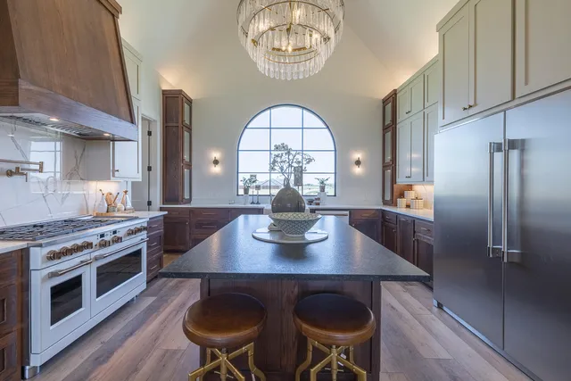 a kitchen with stainless steel appliances granite countertop a refrigerator a stove and white cabinets with wooden floor