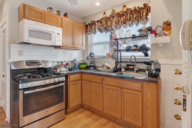 1629 May Street Union, NJ 07083 - Photo 3 of 13 a kitchen with stainless steel appliances granite countertop a stove a microwave and wooden cabinets