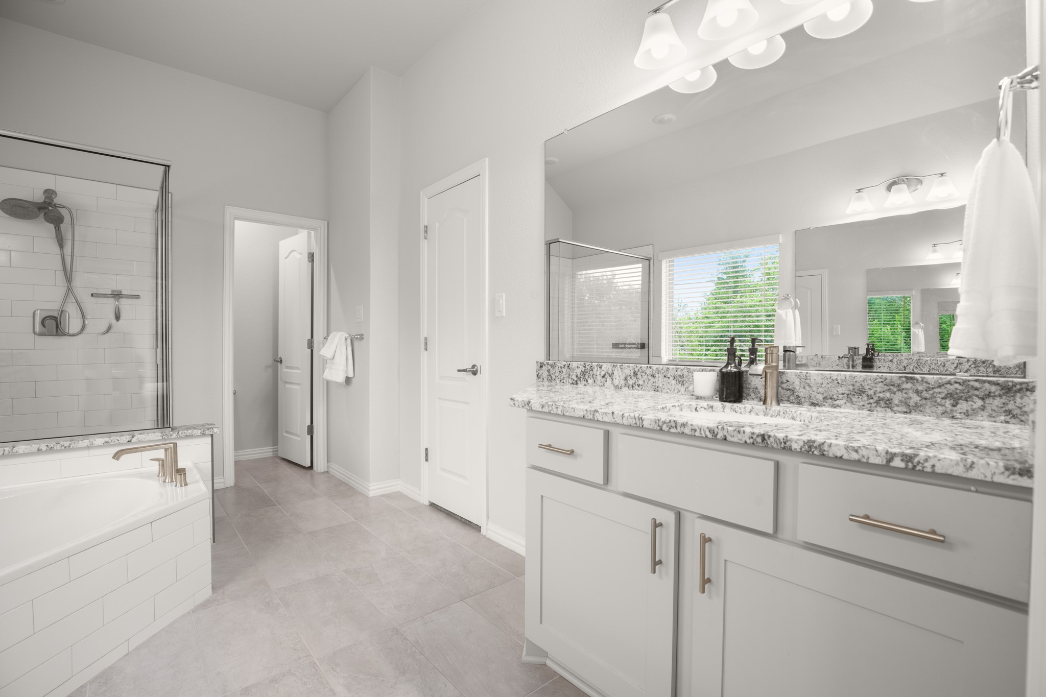 6708 Avila Way Pflugerville, TX 78660 - Photo 19 of 36 a bathroom with a granite countertop sink a large mirror and a bathtub