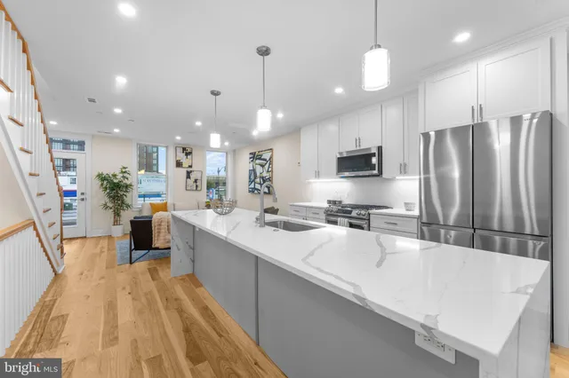 a large kitchen with a large counter top a sink stainless steel appliances and cabinets