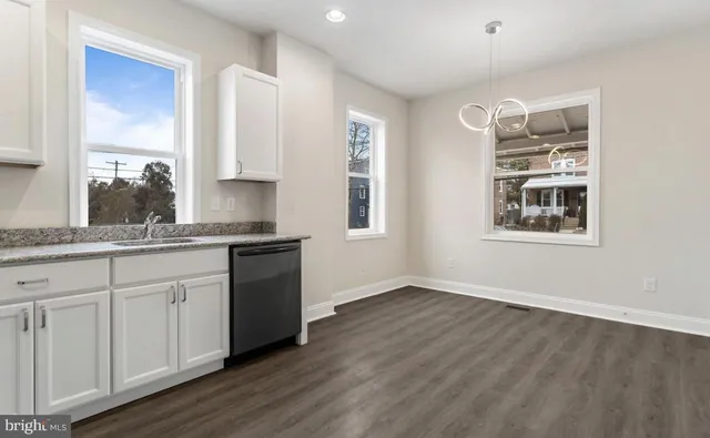 a kitchen with granite countertop white cabinets and wooden floor