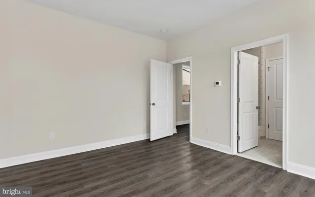 a view of an empty room with wooden floor and closet