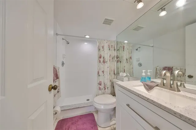 a bathroom with a granite countertop sink a toilet a mirror and shower