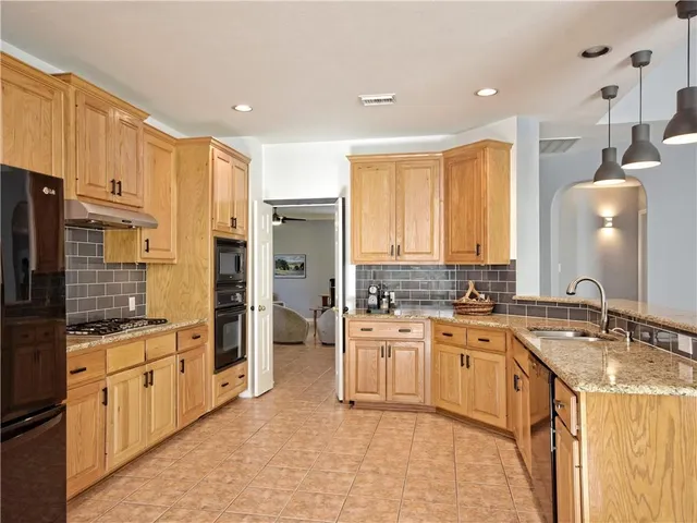 a large kitchen with stainless steel appliances a sink stove refrigerator and cabinets