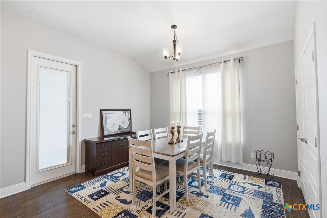 113 Terra Vista Ranch Road Victoria, TX 77904 - Photo 21 of 47 a dining room with wooden floor a chandelier a wooden table and chairs