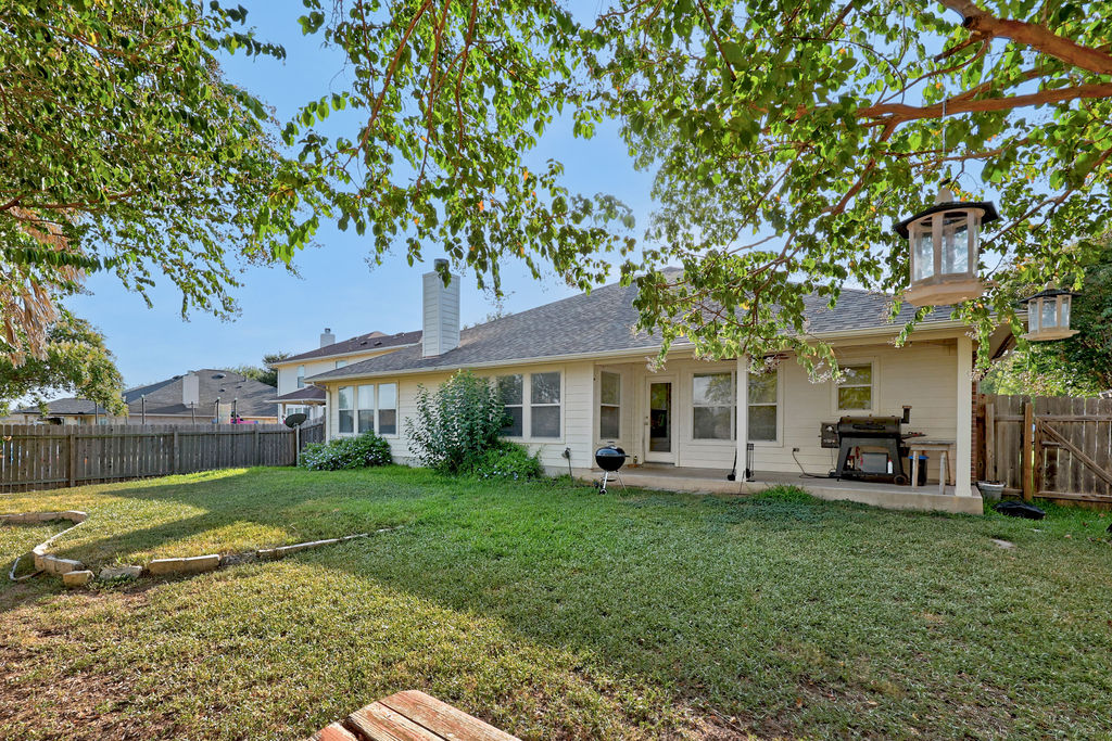 400 Ranier Lane Round Rock, TX 78665 - Photo 31 of 36 Mature trees shade a grassy lawn bordering the rear elevation with its covered patio.