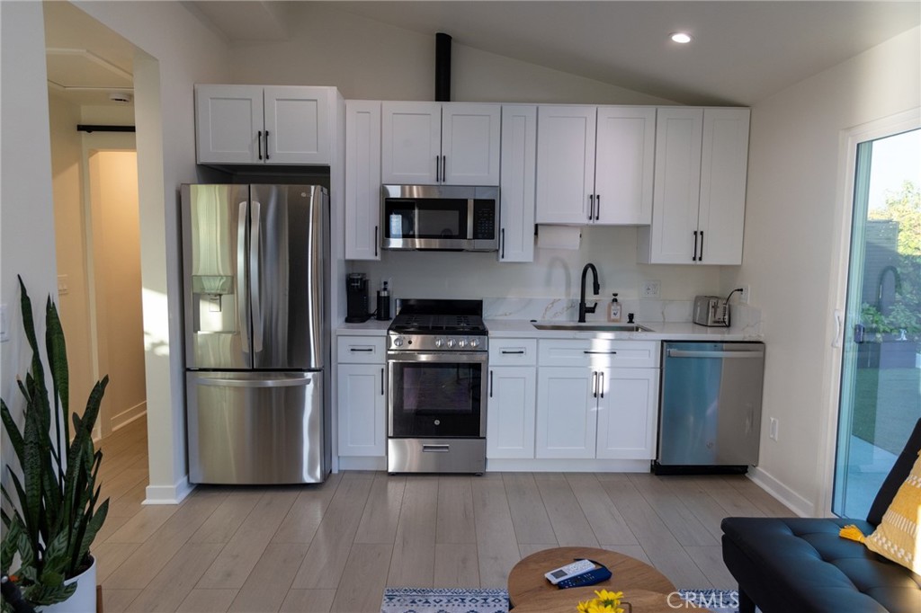 20551 Rhoda Street Woodland Hills, CA 91367 - Photo 4 of 9 a kitchen with a refrigerator stove and white cabinets