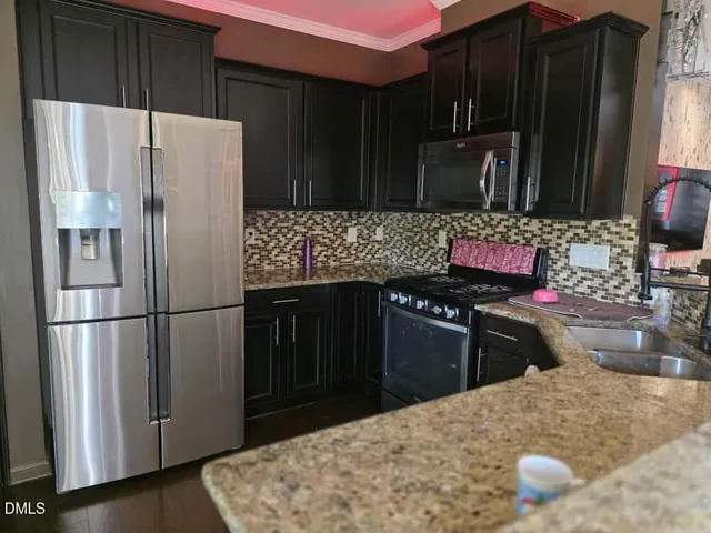 a kitchen with stainless steel appliances granite countertop a refrigerator stove and a sink