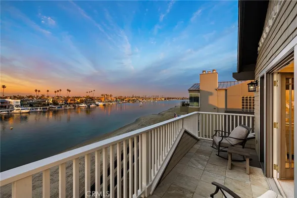 a view of a balcony with wooden chairs and a lake view