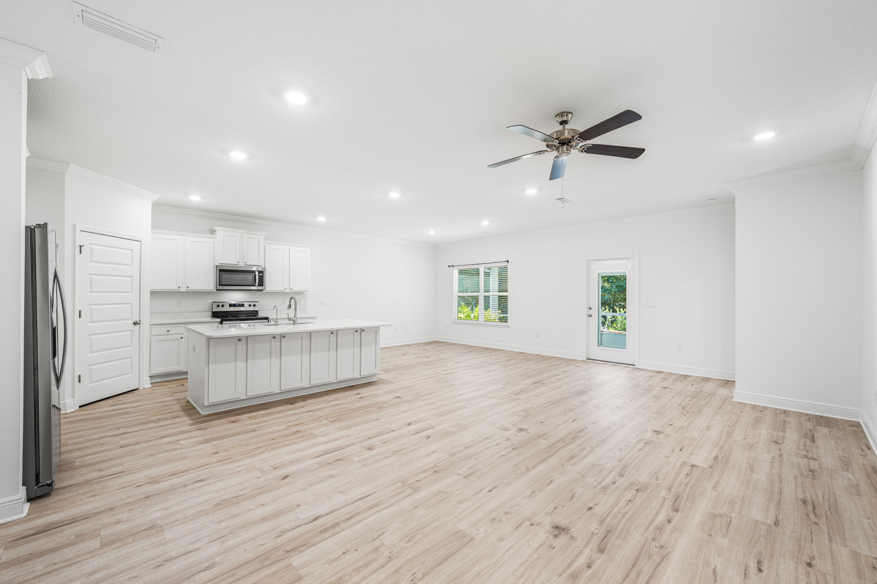157 Jr's Way Santa Rosa Beach, FL 32459 - Photo 13 of 45 a large kitchen with kitchen island a stove a refrigerator a sink and white cabinets with wooden floor