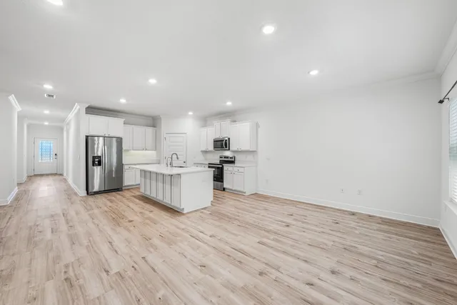 a view of kitchen with kitchen island wooden floor granite counter tops and white cabinets