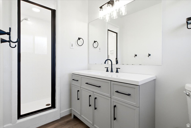1676 East 11245 South Sandy, UT 84092 - Photo 14 of 34 Master Bathroom featuring a gray vanity with a white countertop, matte black fixtures, a shower with a black-framed glass enclosure, and wood-finish flooring